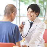 医師が高齢者患者に聴診器で診察を行っている様子